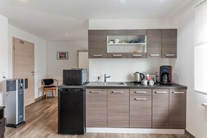 Una cocina moderna con refrigerador, lavavajillas, microondas, cafetera y pileta.