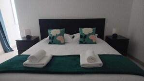 A neatly made bed with two pillows, a green bedspread, and two rolled towels. - Family home for a quiet stay close to all amenities! (Montrichard Val de Cher)