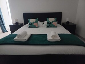 A neatly made bed with two pillows, a green bedspread, and two rolled towels. - Family home for a quiet stay close to all amenities! (Montrichard Val de Cher)