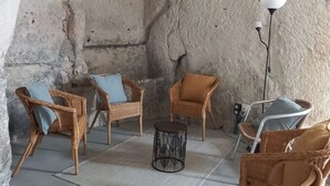 A rustic interior with stone walls, wicker furniture, a small table, and a floor lamp. - Family home for a quiet stay close to all amenities! (Montrichard Val de Cher)