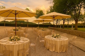 Outdoor round tables with clear chairs and yellow umbrellas, set on a gravel path with trees in the background. - CA SALVA TEOLO:Charming country house nestled in the pleasant Veneto countryside (Veneto)