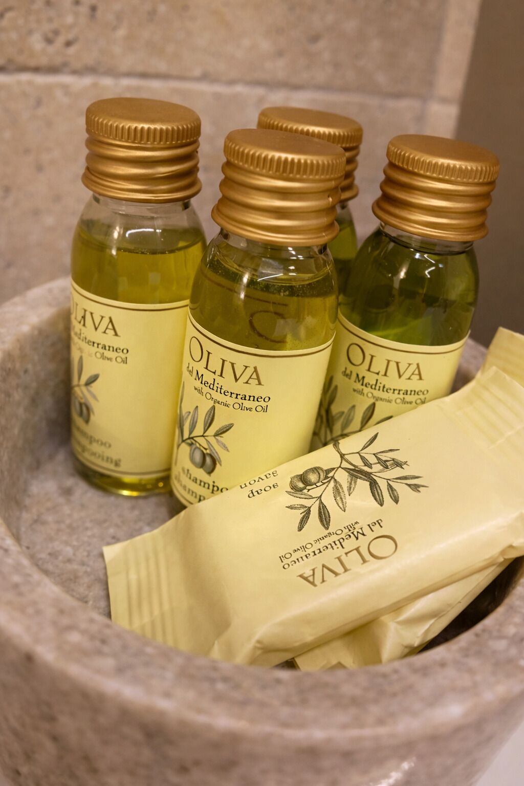 Three bottles of olive oil and a cloth in a stone container.
