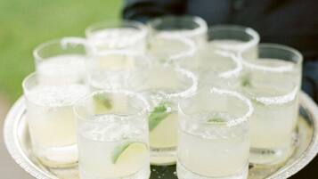 A tray with multiple glasses of a clear beverage, garnished with lime, held by a person.