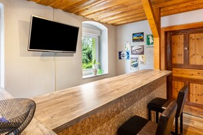 Ein Empfangsbereich mit Holztresen, einem an der Wand befestigten Fernseher, einem Fenster mit Blick auf Grünflächen und einer Tür mit Holzrahmen.