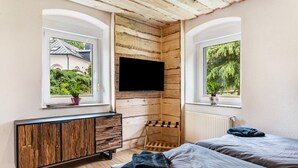 Une chambre avec deux lits, une télévision, une armoire en bois et une fenêtre donnant sur un paysage verdoyant.