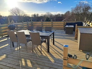 An outdoor deck with a table and chairs, a barbecue grill, and a small seating area. - 4 Star Holiday Home in Lokken (Lokken)
