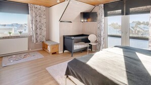 A bedroom with a bed, a desk, a chair, a TV, and a window with a view. - 4 Star Holiday Home in Lokken (Lokken)