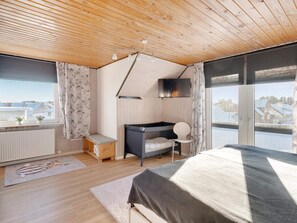 A bedroom with a bed, a desk, a chair, a TV, and a window with a view. - 4 Star Holiday Home in Lokken (Lokken)