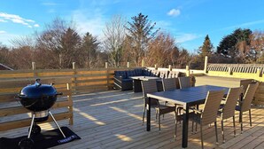 A wooden deck with a grill, a table, and outdoor seating. - 4 Star Holiday Home in Lokken (Lokken)
