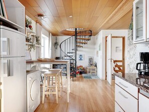 A modern kitchen with wooden flooring, a built-in oven, and a spiral staircase leading to an upper level. - 4 Star Holiday Home in Lokken (Lokken)