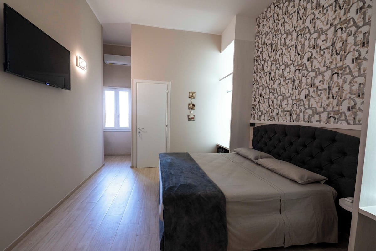 Ein Schlafzimmer mit einem Bett, einer Bank, einem Fernseher und einer Wand mit Muster.