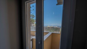Vista a través de una ventana de un balcón con barandilla, un marco de puerta y un cielo despejado.