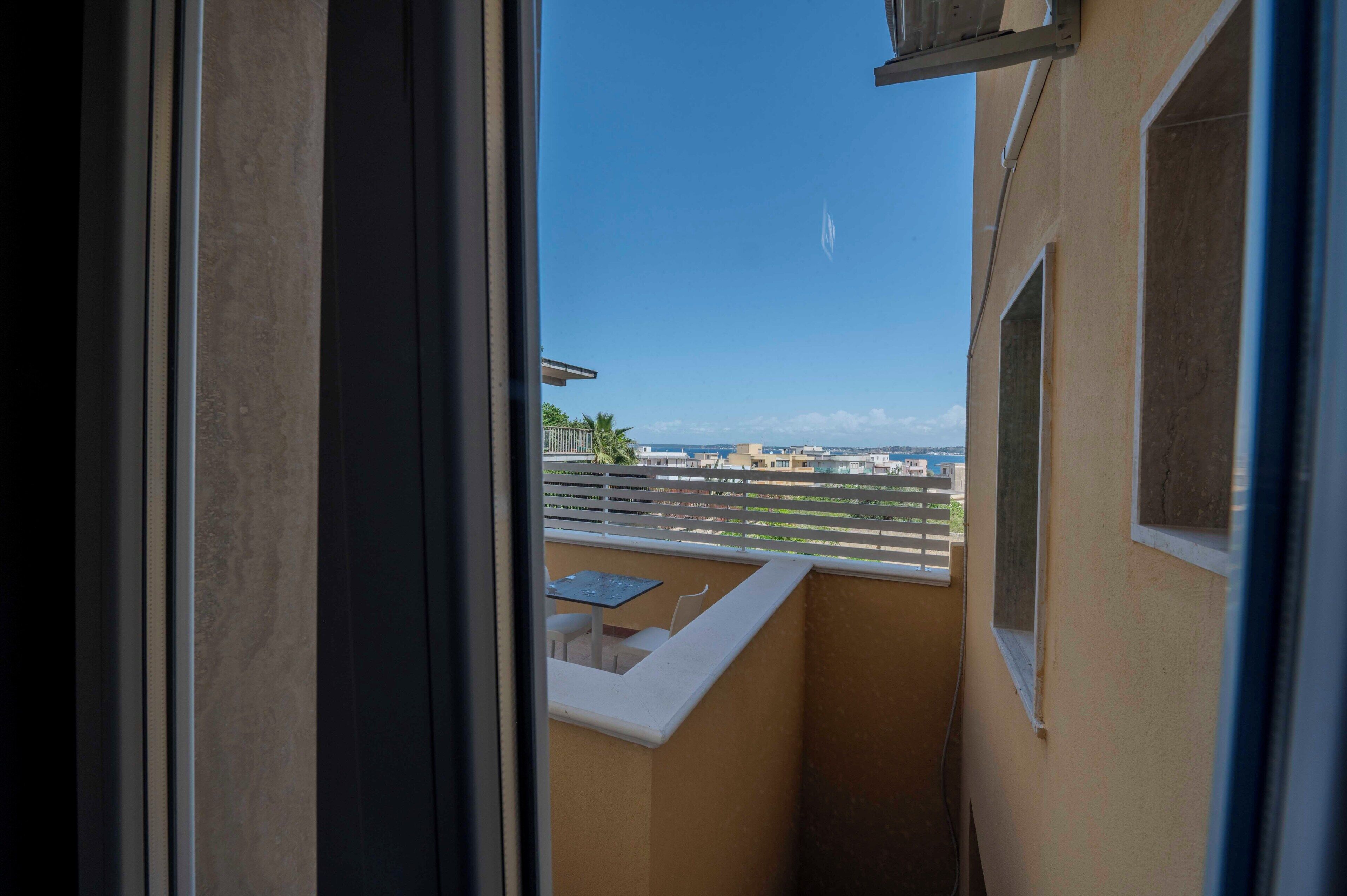 En balkon med udsigt over bybilledet, et lille bord og en stol.