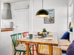 Ein Essbereich mit Holztisch, Stühlen, einer Pendelleuchte, einer Heizung und einem Poster an der Wand.