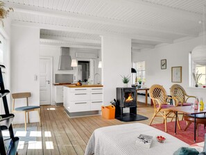 Ein modernes Interieur mit einem zentralen Kamin, Holzdielen und einer Essecke mit Korbstühlen.
