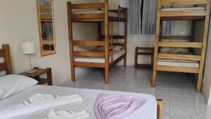 Una habitación de hotel con literas, una cama con una toalla morada, un ventilador de techo y un aire acondicionado.