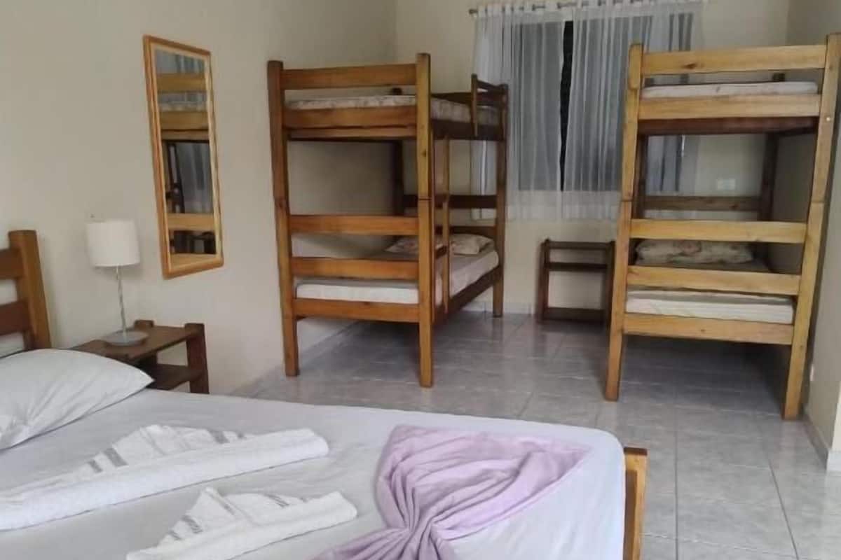 A hotel room with bunk beds, a bed with a purple towel, a ceiling fan, and an air conditioning unit.
