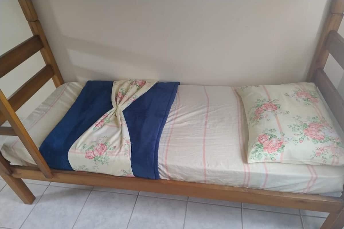 A wooden bunk bed with floral bedding and a blue blanket.