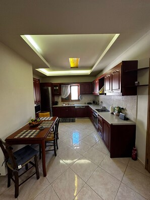 A kitchen with a dining table, chairs, cabinets, and a ceiling light fixture. - Evdokiahouse (Malevizi)