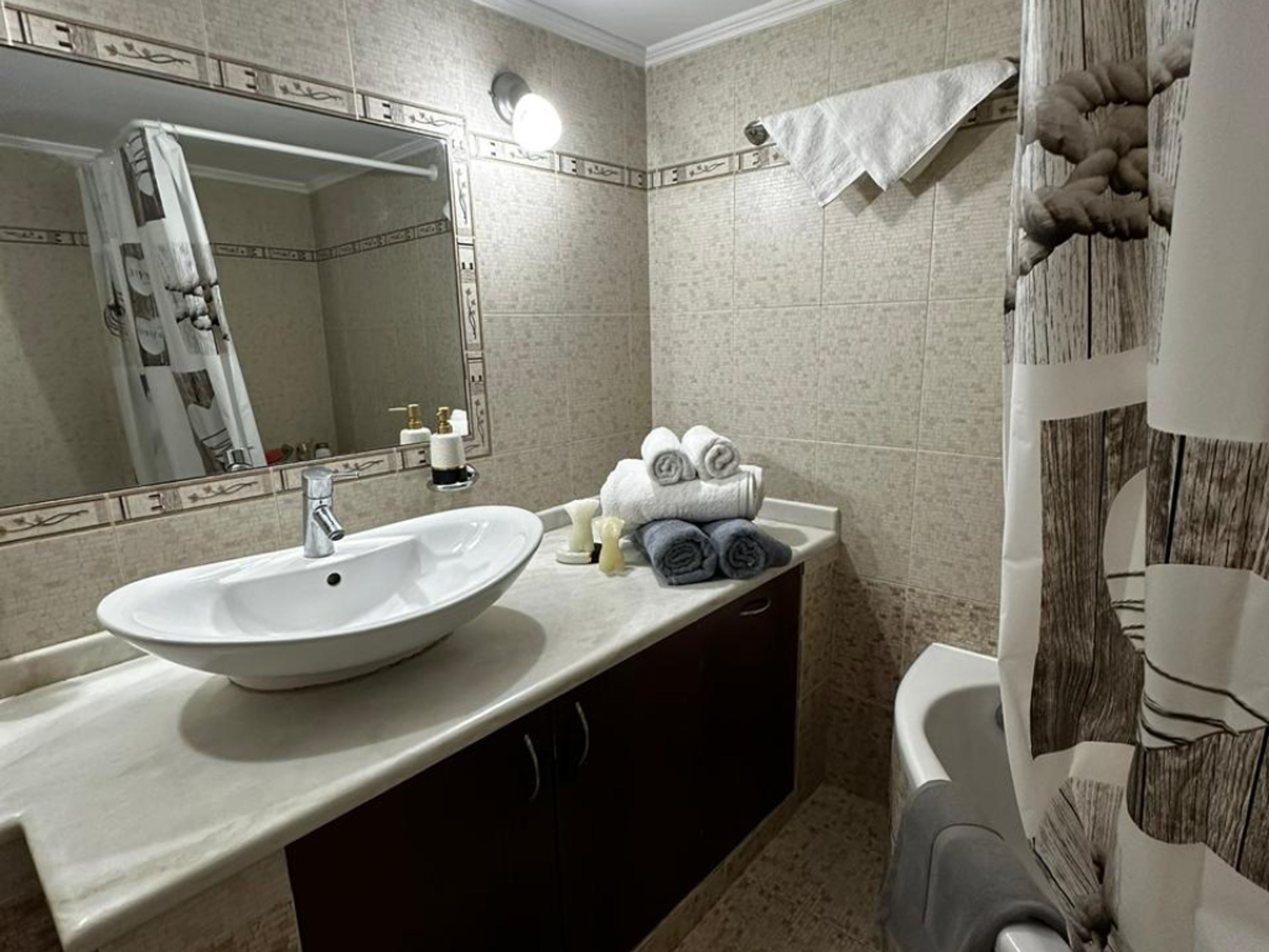 Une salle de bain avec un grand miroir, un lavabo, une baignoire et des serviettes.