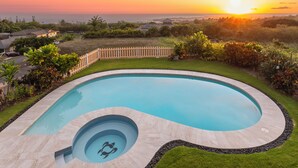 Una piscina dalle linee curve, circondata da un recinto in legno e da una vegetazione rigogliosa.