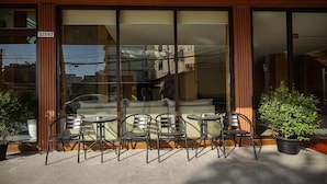 A building with large glass windows, a wooden facade, and outdoor seating with metal chairs and tables. - Room-velin Pattaya Hotel-central Pattaya (Pattaya)