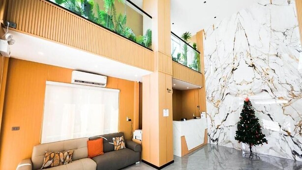 A hotel lobby with a reception desk, a sofa, a small Christmas tree, and a large wall mural. - Room-velin Pattaya Hotel-central Pattaya (Pattaya)