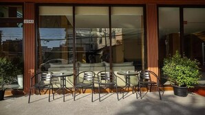 A building with large glass windows, a wooden facade, and outdoor seating with metal chairs and tables. - Room-velin Pattaya Hotel-central Pattaya (Pattaya)