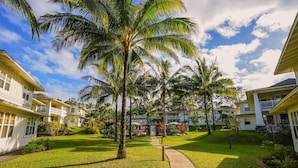 A residential area with multiple two-story houses, a well-maintained lawn, and palm trees. - Modern 2br Princeville Condo, Pool, Hot Tub, Fitness Center (Princeville)