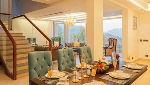A dining area with a table set for four, a staircase, and a view of the outdoors. - ELIVAAS privé Royce Cottage 4BHK Villa (Kasauli)