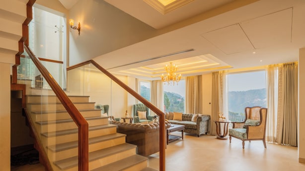 A spacious living area with a staircase, a chandelier, and a view of the outdoors. - ELIVAAS privé Royce Cottage 4BHK Villa (Kasauli)