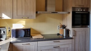 Eine Küche mit Holzausstattung, einer Mikrowelle, einem Backofen von Bosch und einer Kaffeemaschine.