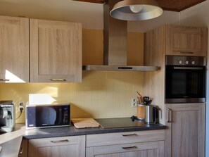 A kitchen with wooden cabinets, a microwave, a Bosch oven, and a coffee maker.