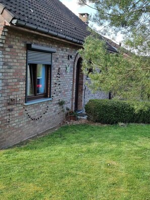 A brick house with a window, a door, and a small garden.