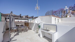 A rooftop terrace with a satellite dish, outdoor furniture, and a view of a church with purple flowers. - Holiday Home 'Lanzarote' with Private Terrace, Wi-Fi and Air Conditioning (Alvor)