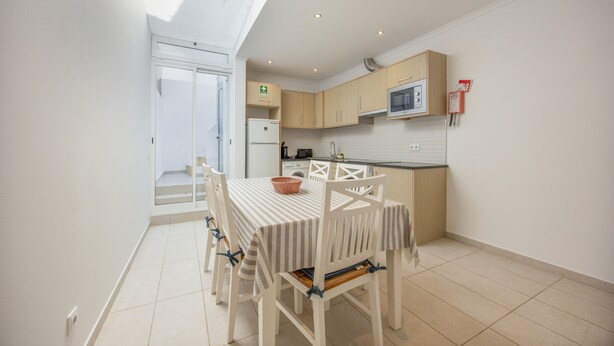 A modern kitchen with a dining table and chairs, a microwave, and a refrigerator. - Holiday Home 'Lanzarote' with Private Terrace, Wi-Fi and Air Conditioning (Alvor)