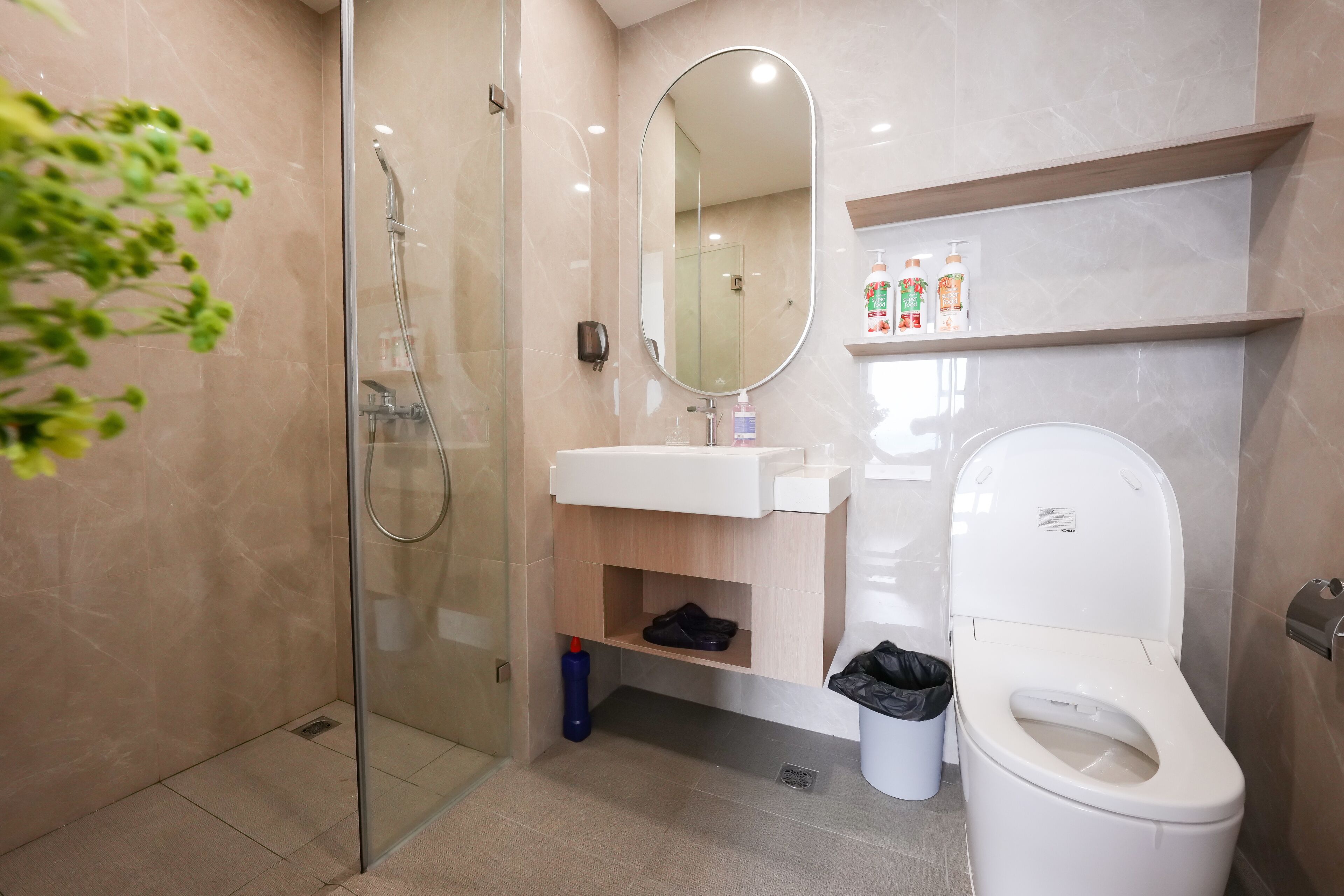 A modern bathroom with a glass-enclosed shower, a white sink, a mirror, and a toilet.