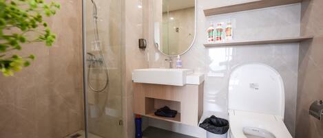 A modern bathroom with a glass-enclosed shower, a white sink, a mirror, and a toilet.