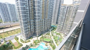 A high-rise residential building with multiple balconies, a swimming pool, and a landscaped area with palm trees. - Magnolia Vinhomes Apartment (Ho Chi Minh City)