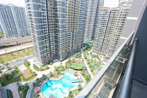 Um edifício residencial alto com várias varandas, uma piscina e área ajardinada com palmeiras.