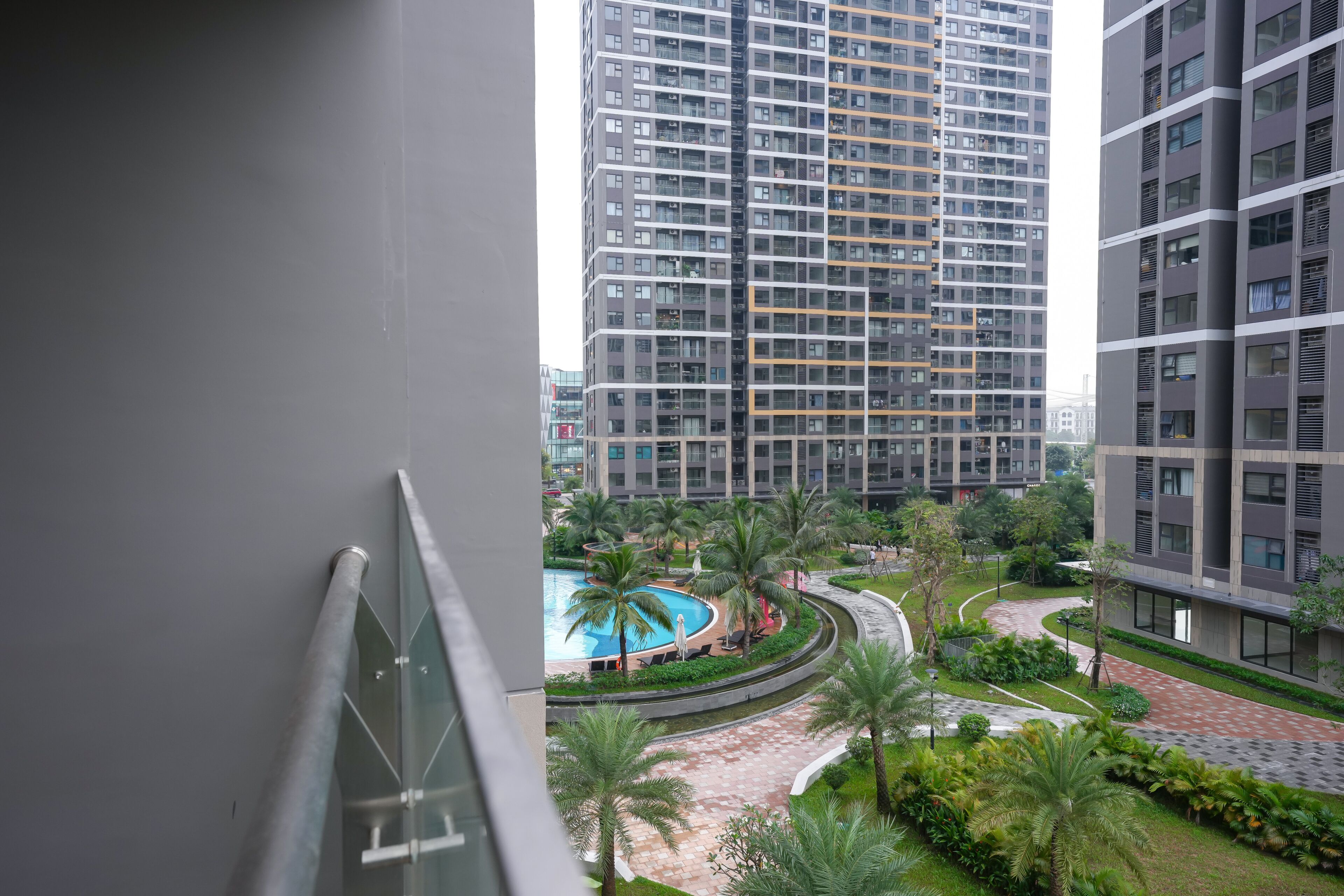 A residential building with a pool, palm trees, and a curved walkway.
