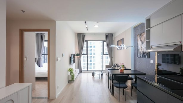 A modern kitchen with a dining area, a TV, and a view of the city. - Magnolia Vinhomes Apartment (Ho Chi Minh City)