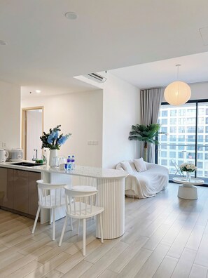 A modern living room with a dining area, a sofa, and a large window with a view.
