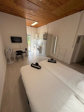 A modern hotel room with a large bed, a TV, a desk, and a kitchenette. - Studios 54 (Villerupt)