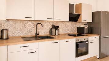 A modern kitchen with white cabinets, a stainless steel sink, and a built-in oven.