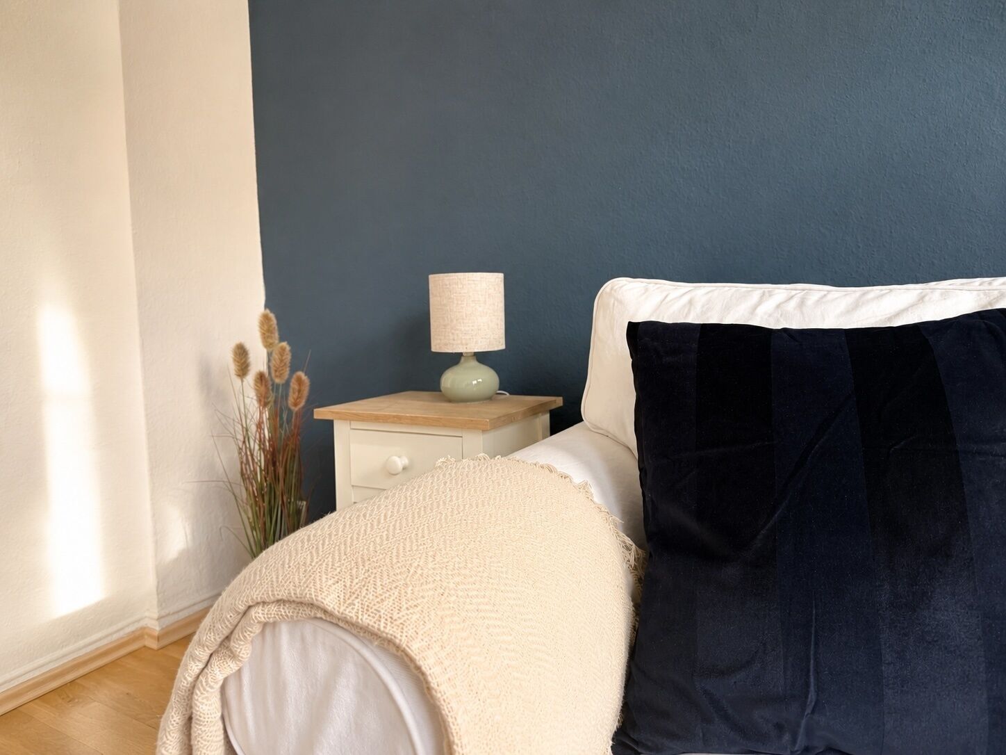 Ein Schlafzimmer mit einem Bett, einem Nachttisch mit Lampe und einer Wand mit Struktur.