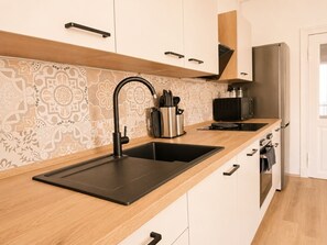 Een moderne keuken met een zwart spoelgedeelte, roestvrijstalen apparatuur en een decoratieve spatwand.