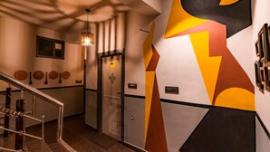 En modern hiss med en väggdesign i geometriskt mönster, ett metallräcke och en taklampa.