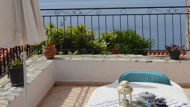 A balcony with a view of the sea, a table with a lantern, and potted plants. - DIAMOND VIEW (Lesvos)