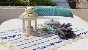 A table with a lantern, a bouquet, and a polka-dotted cushion on a balcony overlooking a body of water and mountains. - DIAMOND VIEW (Lesvos)
